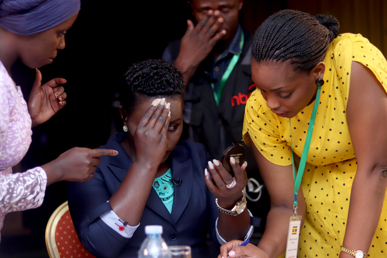 Senior journalist Mildred Tuhaise (centre) refreshes her makeup during a short break in filming as her director (in yellow dress) takes her through the key points for the next segment. Image from The Network by Stuart Tibaweswa. 